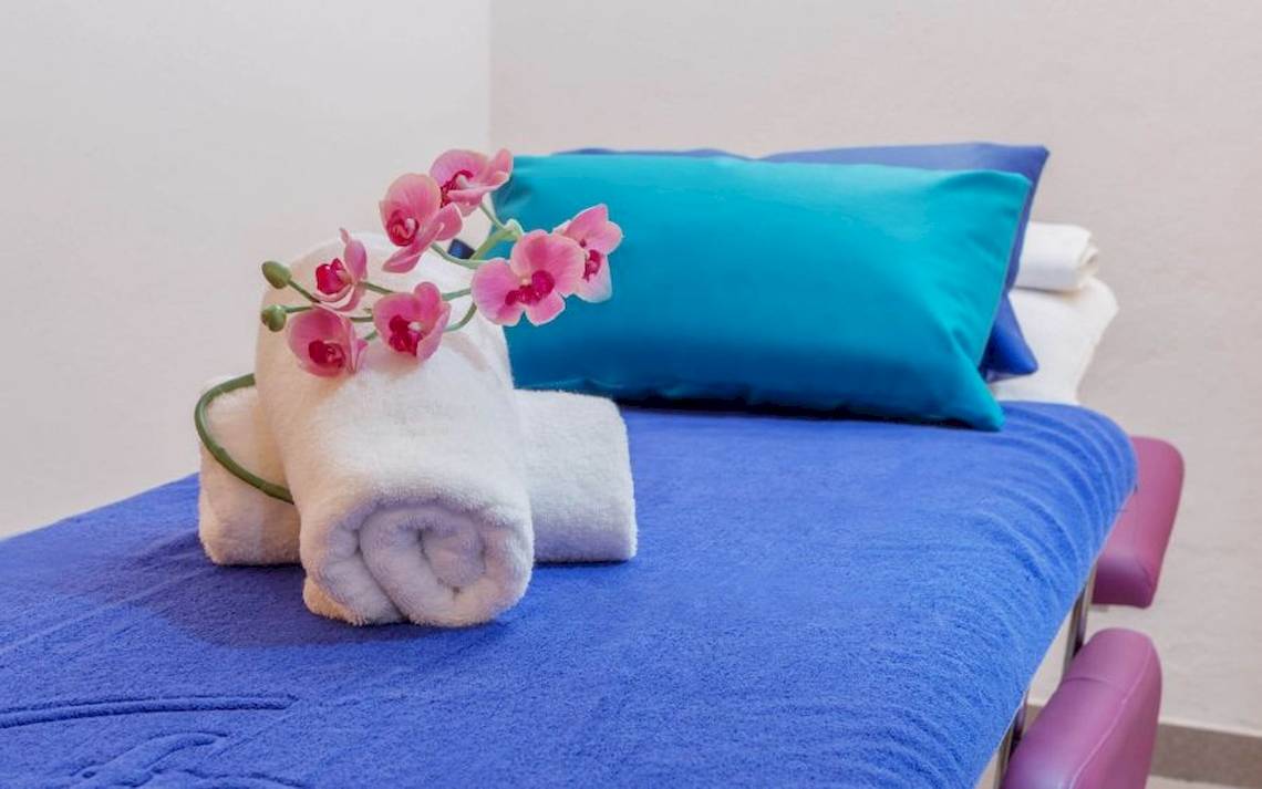 Ein Hotelzimmer mit einem blauen Bett, blauen Kissen und Orchideen auf dem Bett.