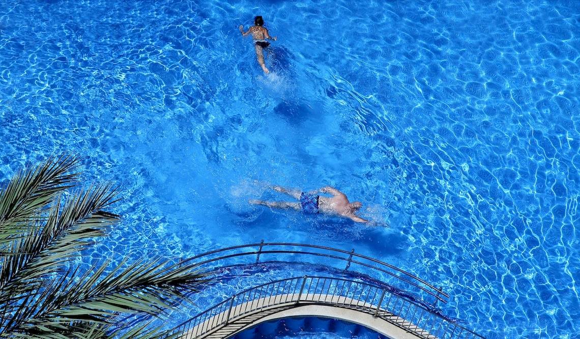Zwei Leute schwimmen im Pool vom Cosmopolitan Hotel, eine Frau oben und ein Mann unten.