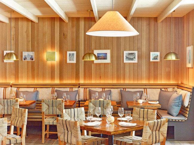 Innenansicht des Restaurants im 1 Hotel South Beach mit hölzernen Wänden, Sitzgelegenheiten und Tischen.