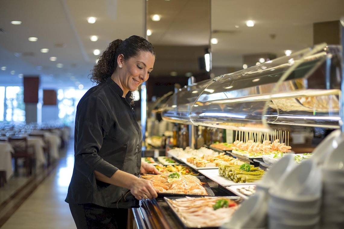 Eine Mitarbeiterin im Hipotels Flamenco serviert Essen an einem Buffet.