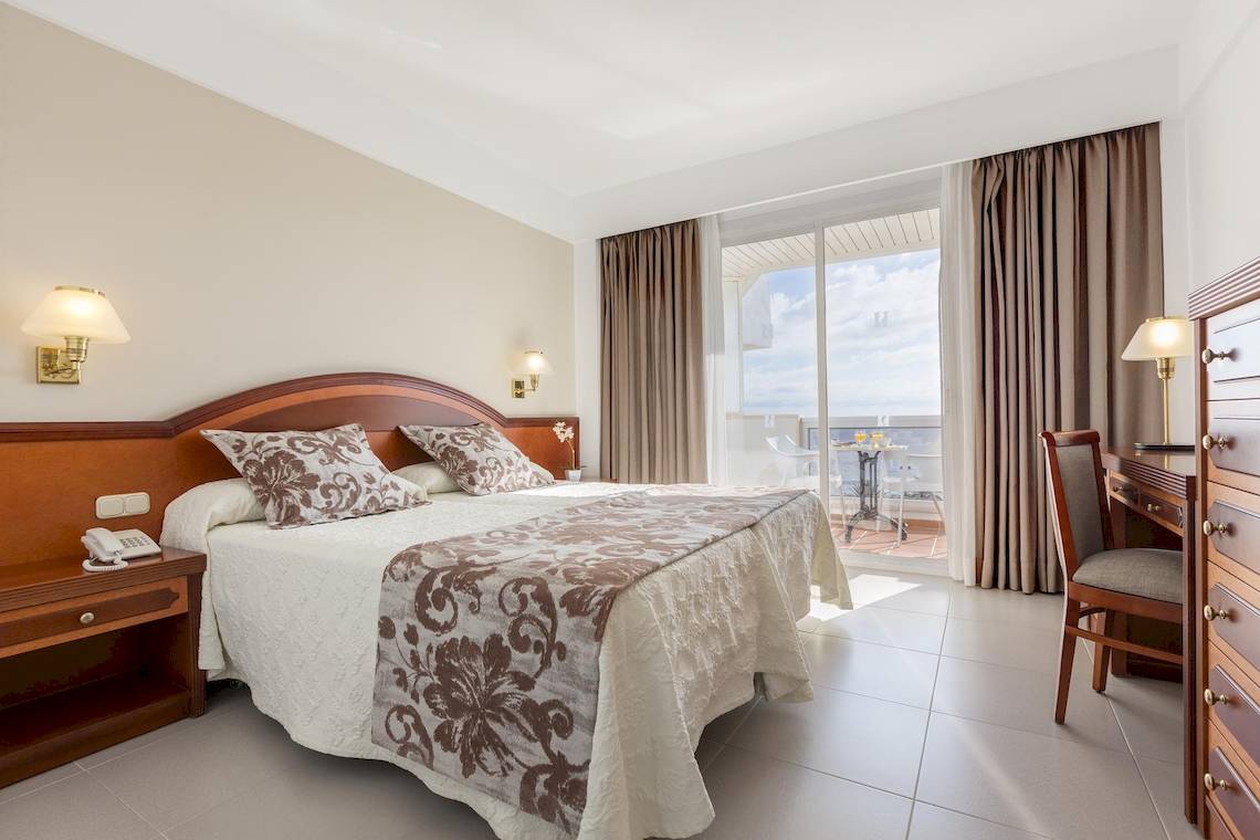 Hotelzimmer im Hipotels Flamenco mit Bett, Schreibtisch, Telefon und Balkon.