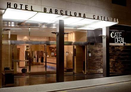 Außenansicht des Hotel Barcelona Catedral mit heller Beleuchtung und Glastüren am Eingang.