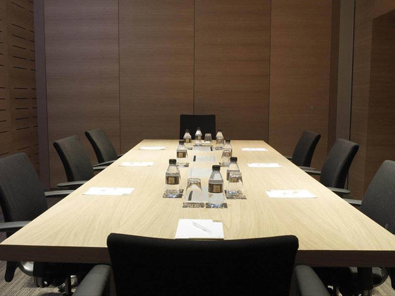 Ein Konferenzraum im Hotel Barcelona Catedral mit einer langen Tabelle und leeren Stühlen.