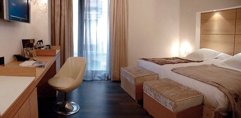 Hotelzimmer im Barcelona Catedral mit Schreibtisch, Stuhl, Betten und Fernseher.