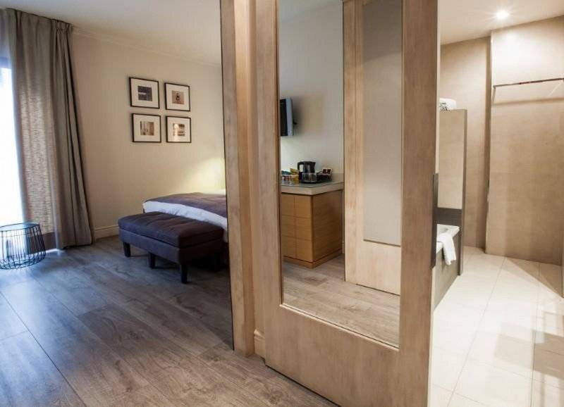 Innenansicht eines Zimmers im Barcelona Catedral Hotel mit Bett, Ottomane und Badezimmerspiegel.