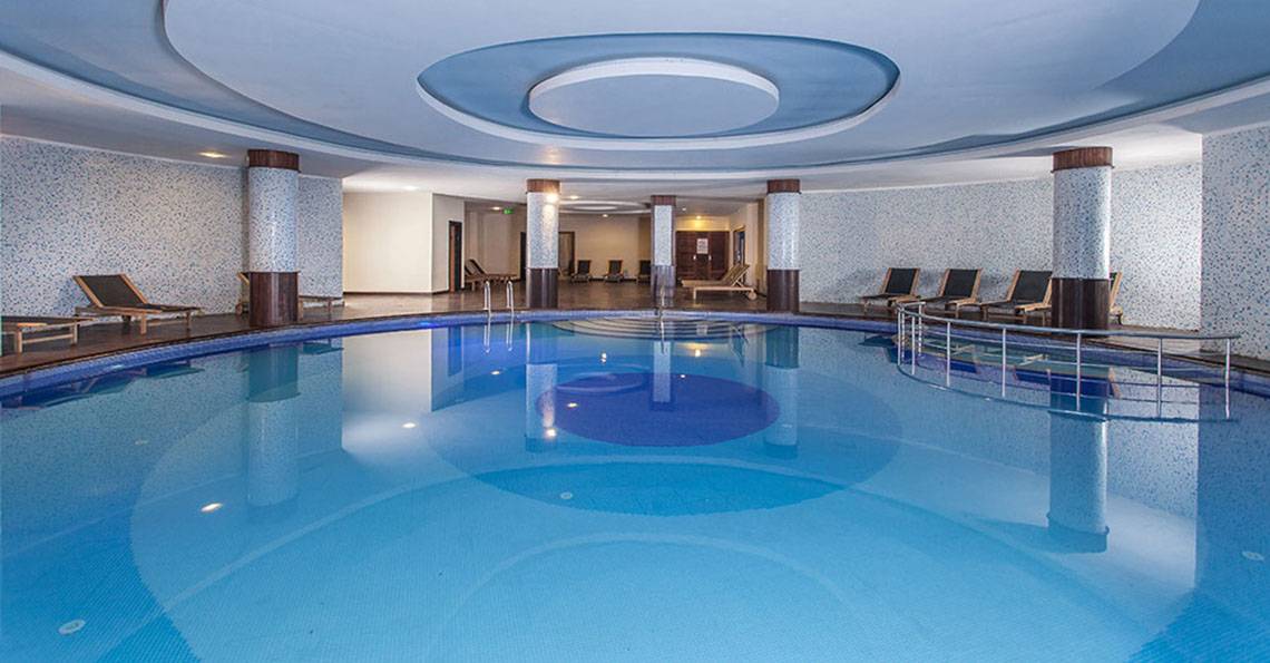Innenpool des Sultan of Side Hotels mit blauem Wasser und Lounge-Liegen