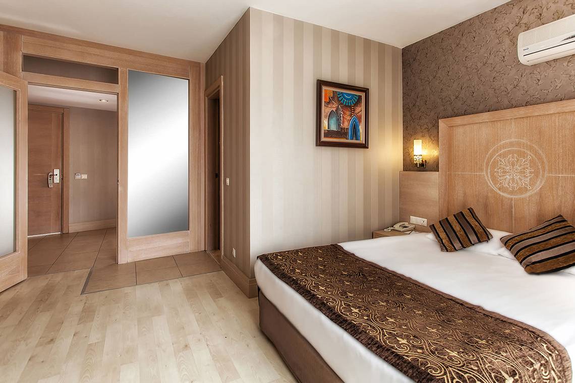 Suite Zimmer im Sultan of Side Hotel mit Bett, Kissen, Decken und Wanddekoration.