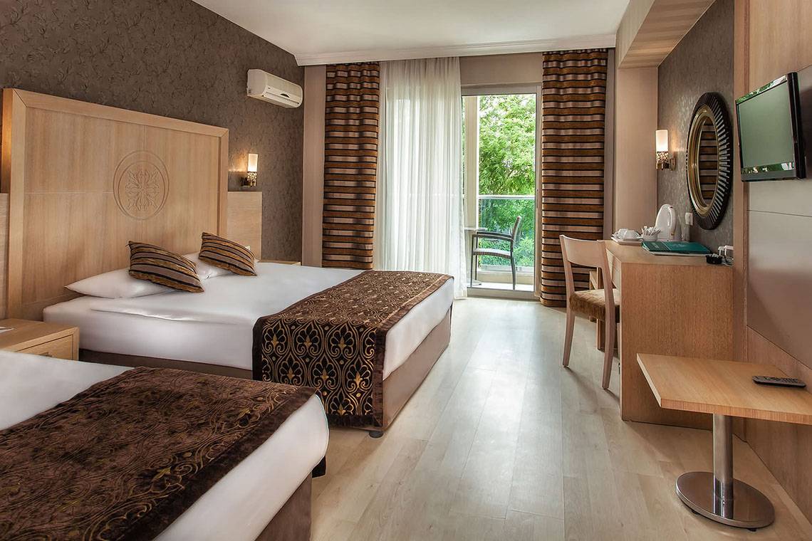 Doppelzimmer im Sultan of Side Hotel mit zwei Betten, einem Schreibtisch und einem Balkon.