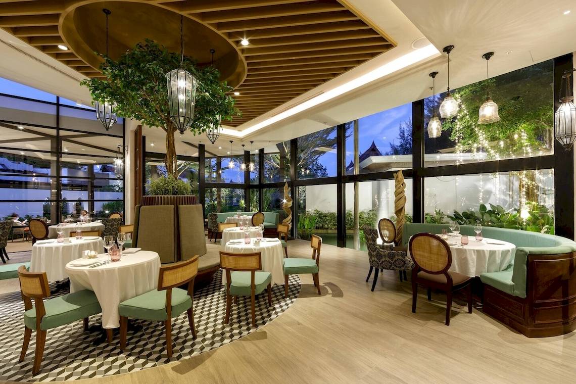 Innenbereich des JW Marriott Khao Lak Resort & Spa Restaurants mit modernem Design, grünen Möbeln und großen Fenstern.