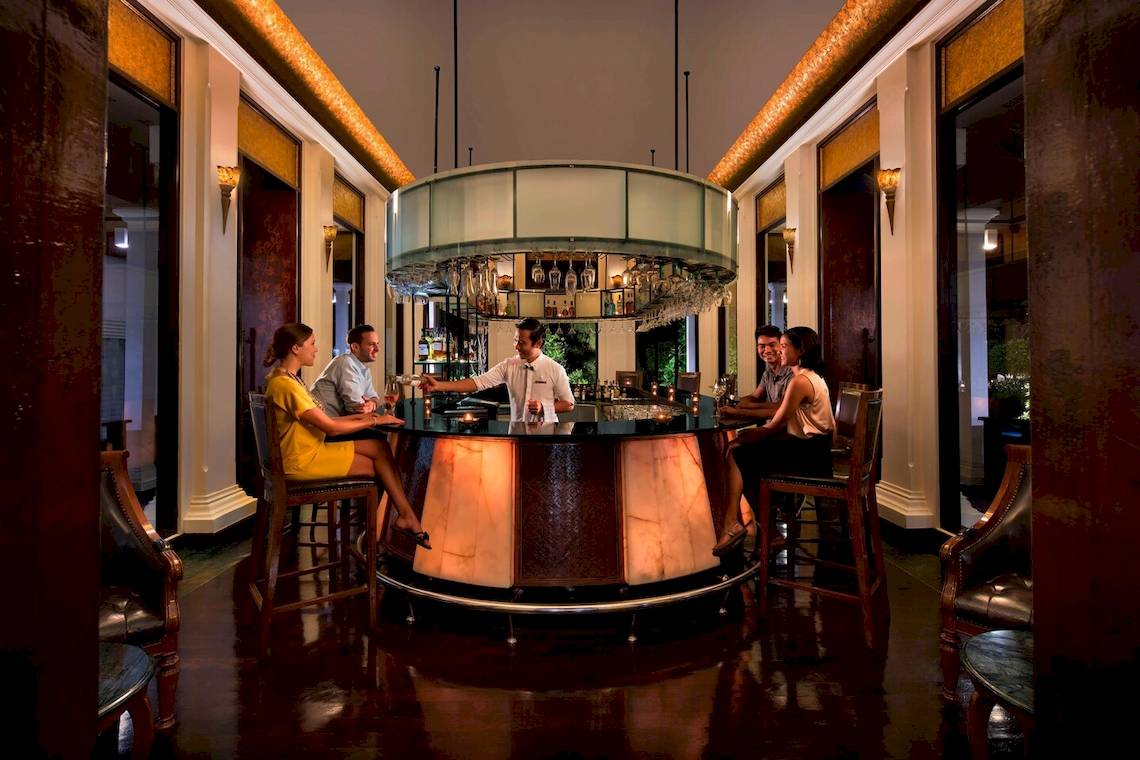 Bar im JW Marriott Khao Lak Resort & Spa mit einem Barkeeper und Gästen.