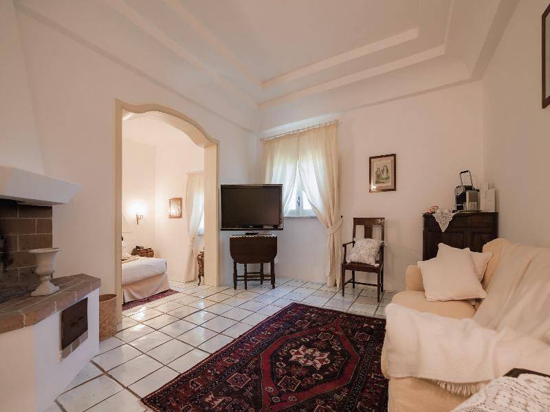 Il Melograno Hotel Wohnzimmer mit Couch, Fernseher, Kamin und Tisch