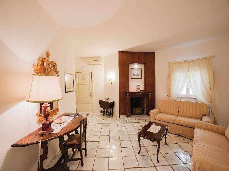Wohnzimmer im Hotel Il Melograno mit Sofas, Kamin, Tisch und Stuhl.