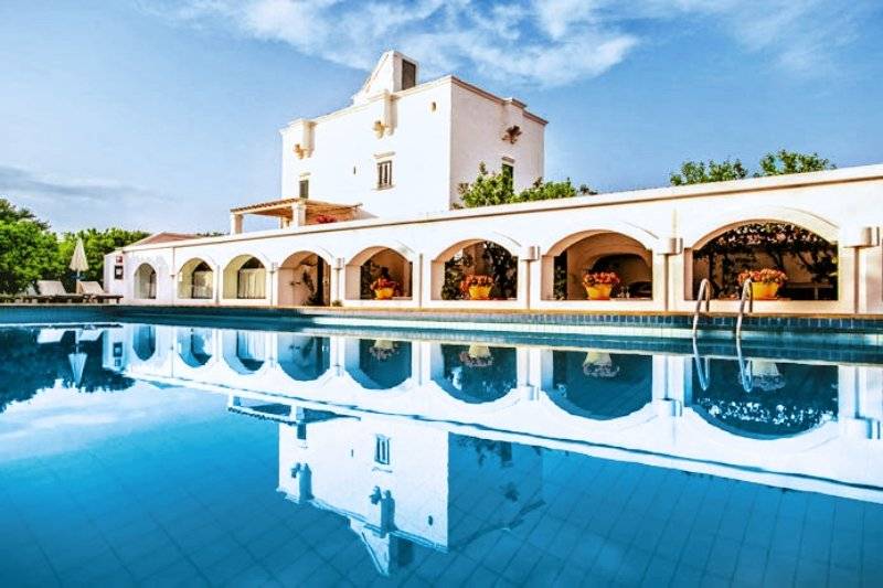 Außenansicht des Hotels Il Melograno mit Pool und weißem Gebäude im Hintergrund