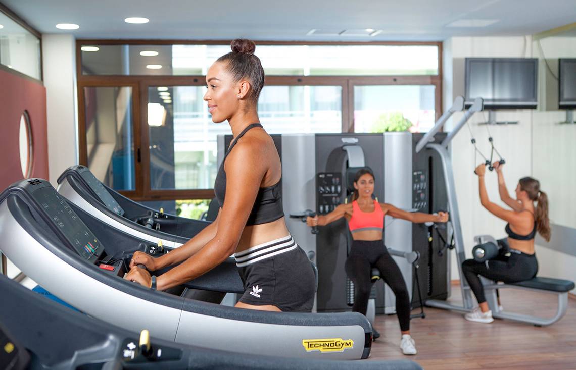 Frauen trainieren im Fitnesscenter des Blue Lagoon Resorts auf Laufbändern und mit Gewichten.