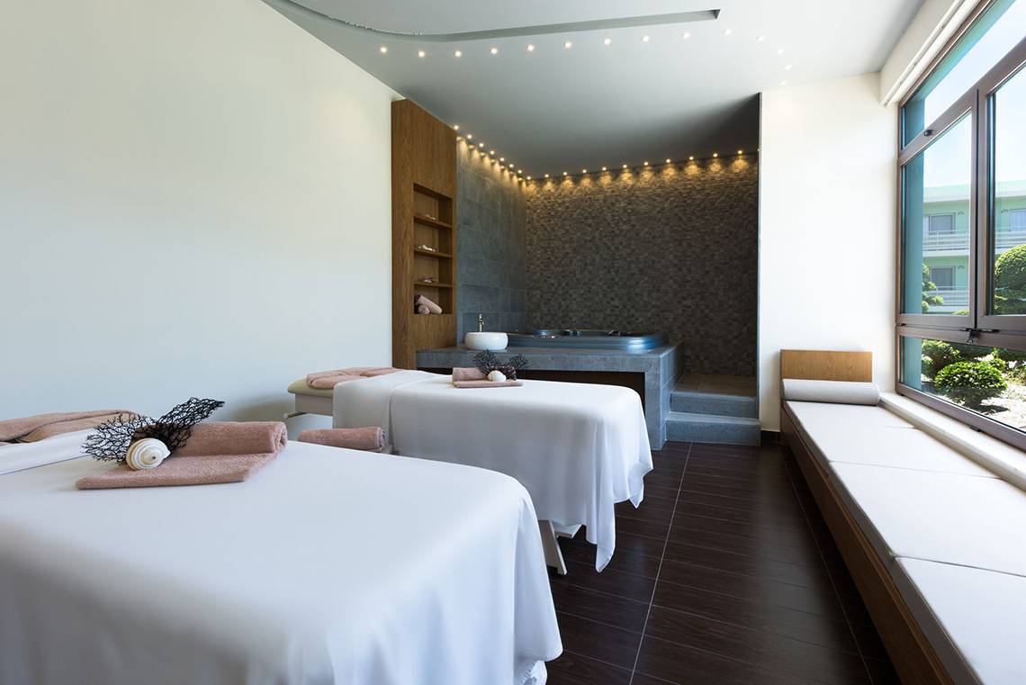 Massageraum im Blue Lagoon Resort mit zwei Massagetischen, Whirlpool und Fenstern.