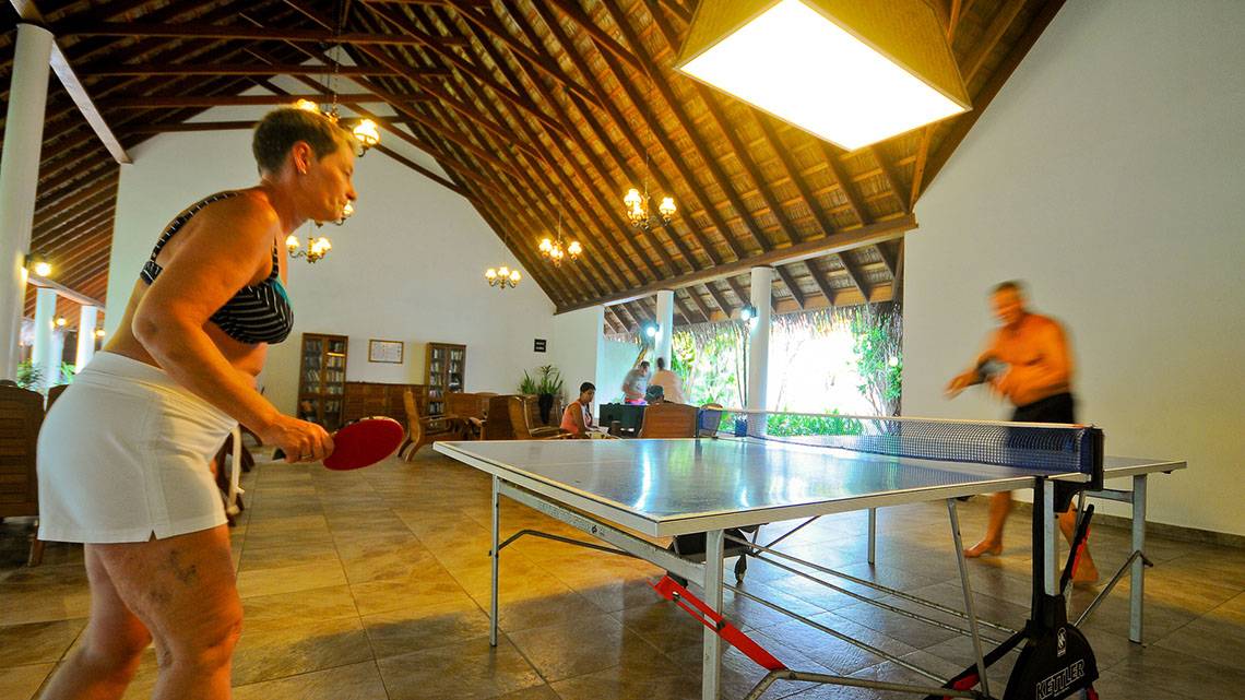 Indoor Ping-Pong Spiel im Fihalhohi Island Resort mit einer Frau und einem Mann.