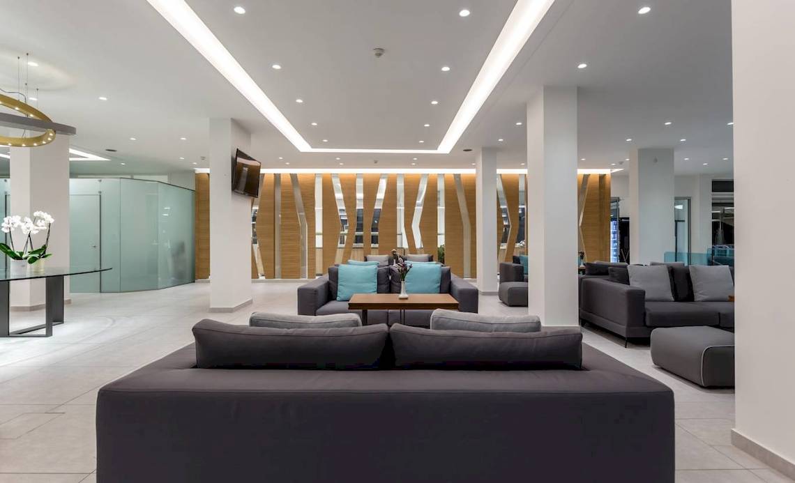 Innenansicht der Lobby des Acharavi Beach Hotel mit modernen Möbeln und Holzelementen.