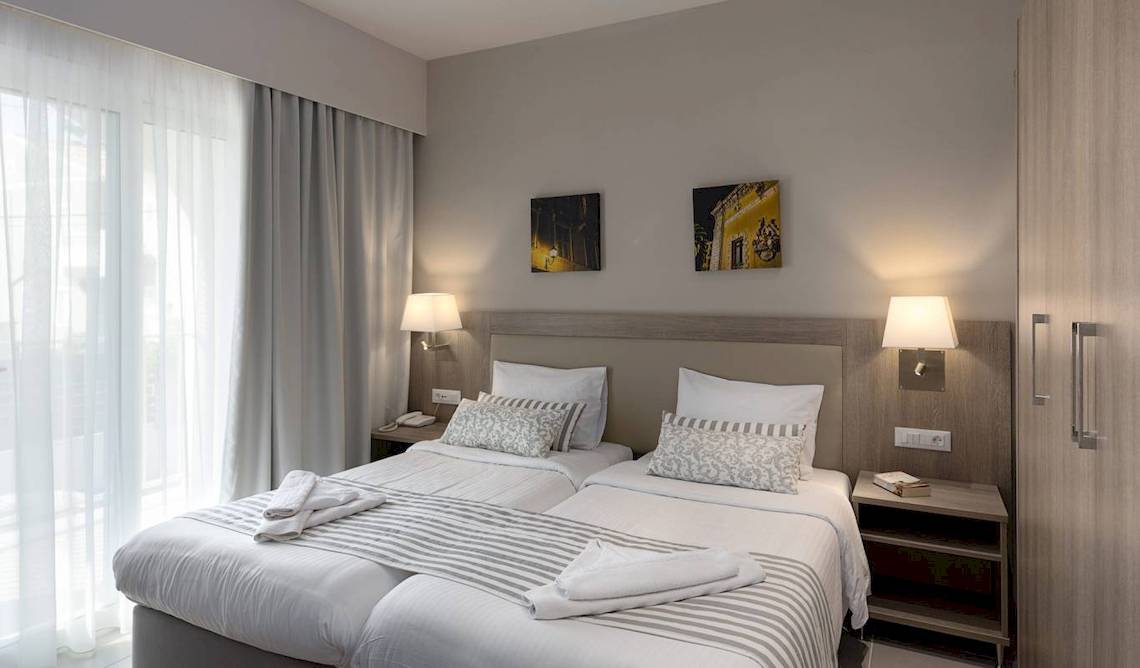 Doppelzimmer im Acharavi Beach Hotel mit zwei Betten, weißem Bettwäsche und Dekor.