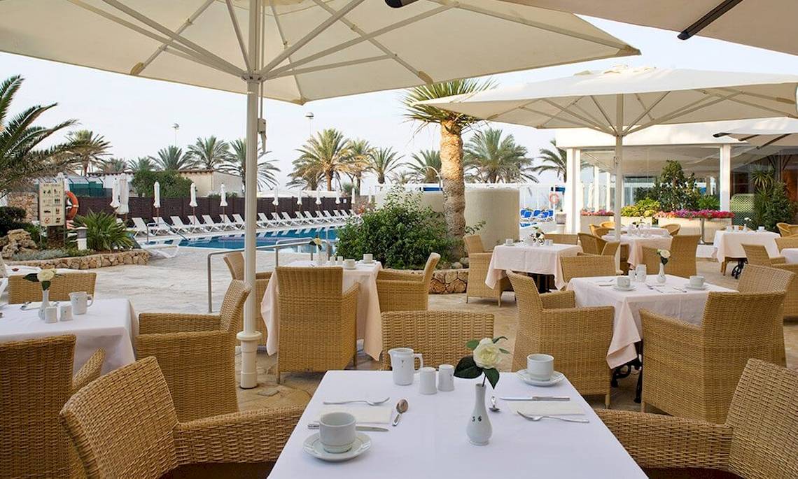 Außenbereich des Restaurants im HM Gran Fiesta Hotel mit Tischen, Stühlen und Sonnenschirmen.