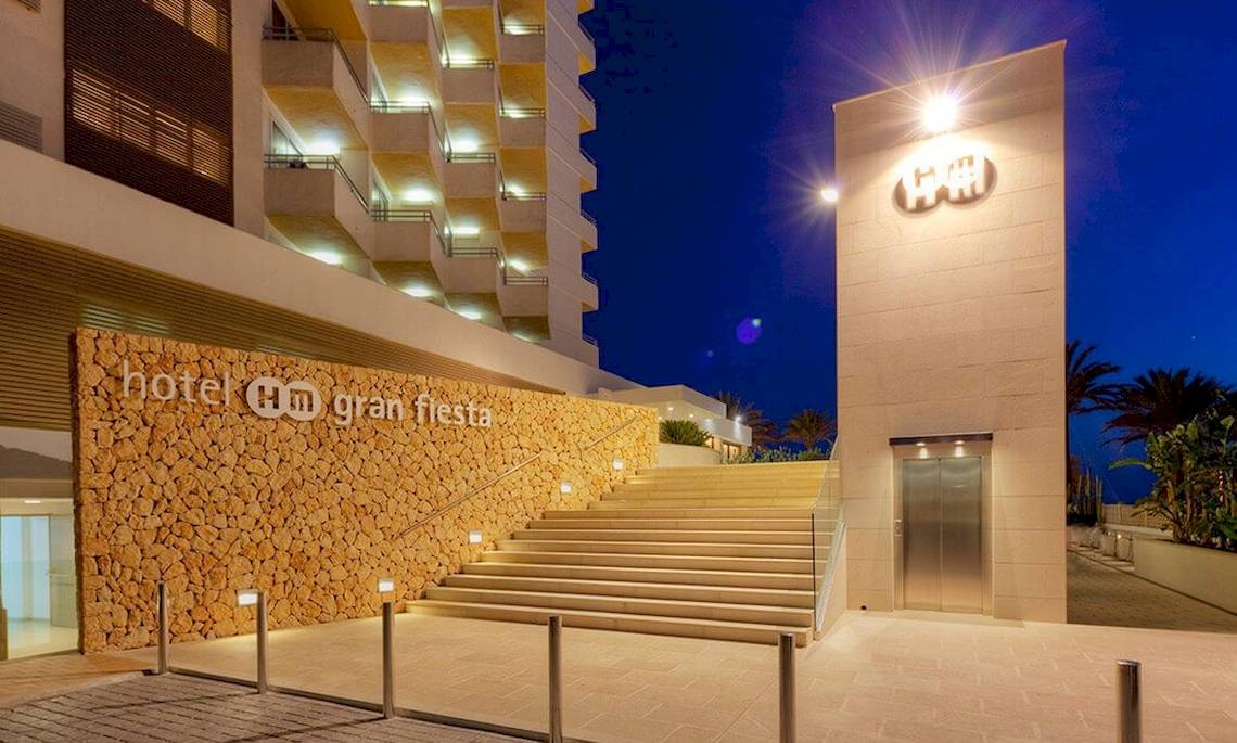 Der Eingang des HM Gran Fiesta Hotels mit Steinwand und beleuchteter Treppe bei Nacht.
