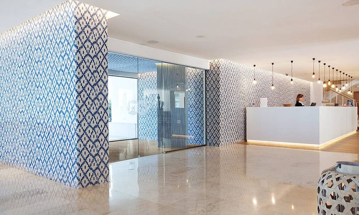 Empfangsbereich des HM Gran Fiesta Hotels mit blau-weißen Wandmustern und einer Rezeptionistin.