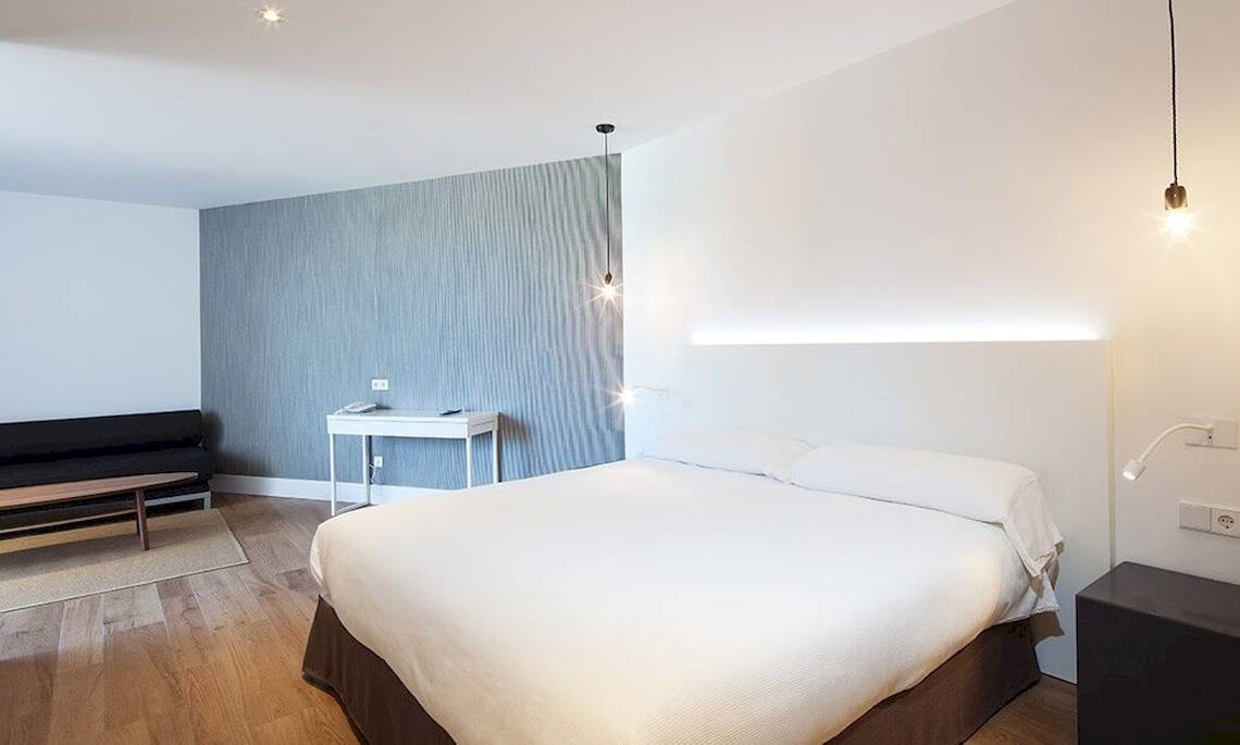 Innenansicht eines Schlafzimmers im HM Gran Fiesta Hotel mit einem Bett, Möbeln und einer Wandgestaltung.