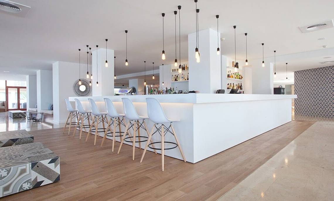 Innenbereich der Bar im HM Gran Fiesta Hotel mit weißen Stühlen und Theke.