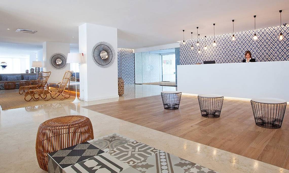 Lobby des HM Gran Fiesta Hotels mit Rezeption, Sitzmöbeln und blau-weißem Wandmuster.