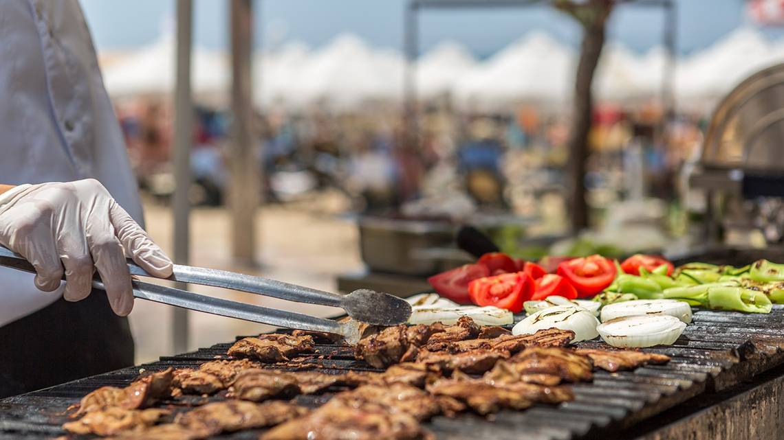 Ein Koch grillt Fleisch und Gemüse auf einem Grill im Freien im Villa Side Residence Hotel.