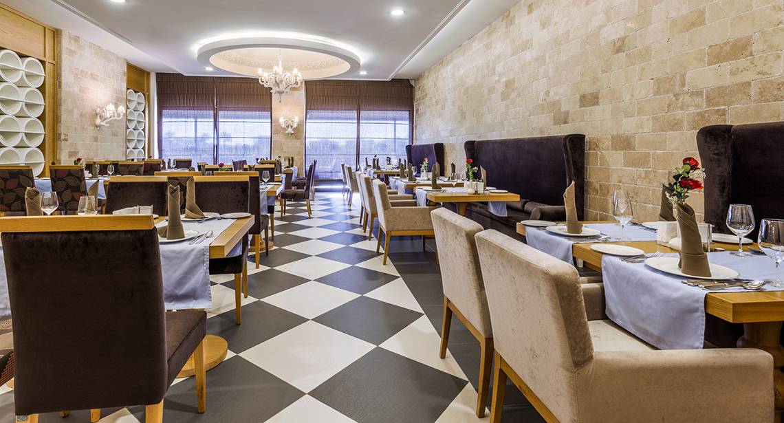 Innenansicht des Restaurants der Villa Side Residence mit gemustertem Boden und elegant eingerichteten Tischen.