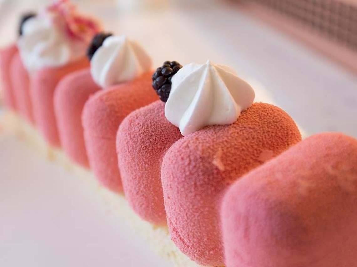Reihe von rosa Desserts mit weißer Creme und schwarzen Beeren oben, im Cactus Mare Hotel.
