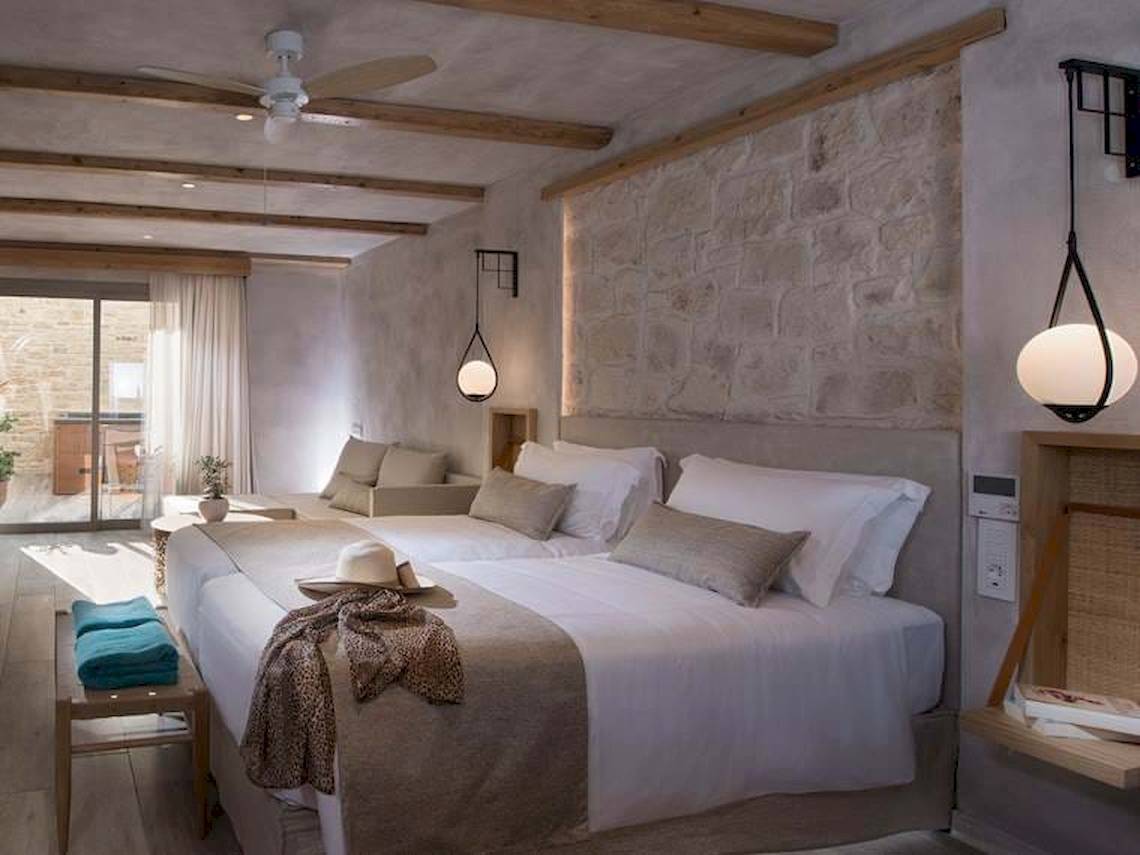 Doppelbett-Zimmer im Hotel Cactus Mare mit steinerner Wand, Deckenventilator und Lampen.