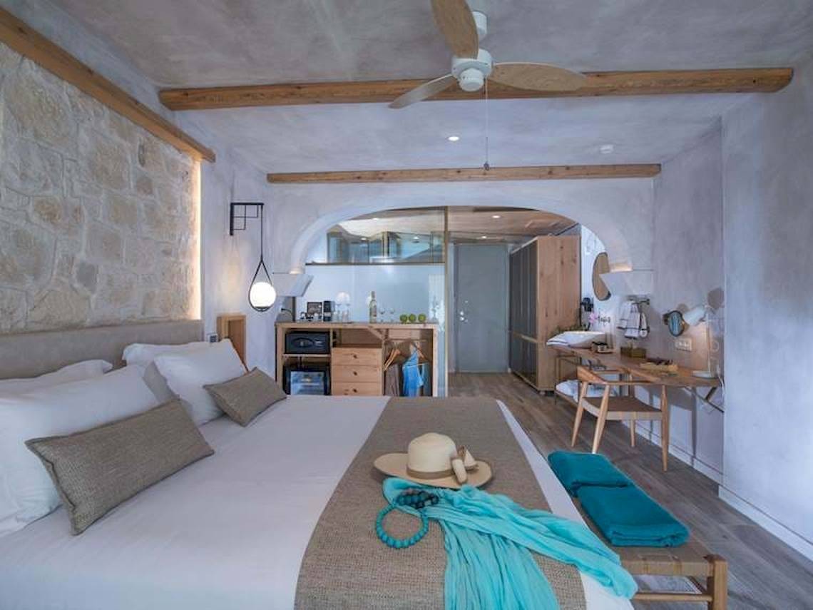 Innenansicht eines Schlafzimmers im Cactus Mare Hotel mit Bett, Schreibtisch, Kleiderschrank und Deckenventilator.