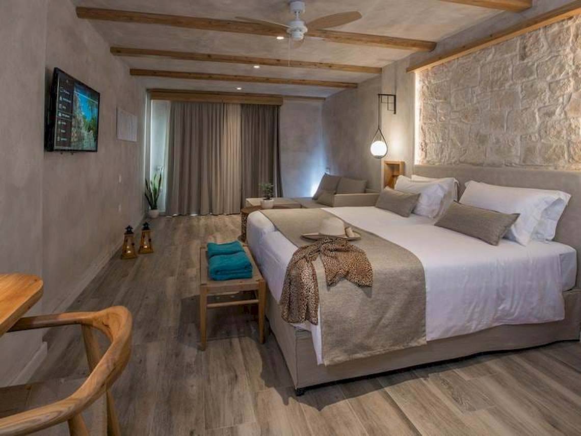Innenansicht eines Zimmers im Cactus Mare Hotel mit Bett, Fernseher und Holzmöbeln.