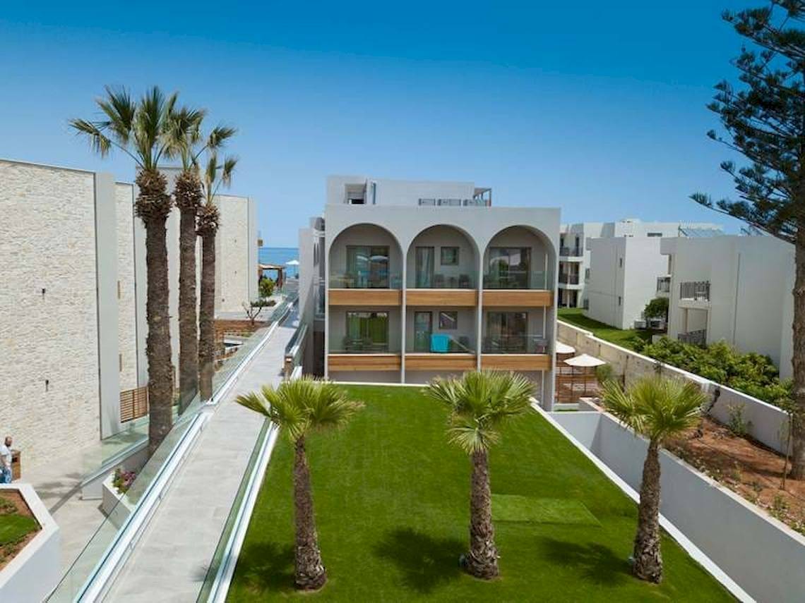 Außenansicht des Cactus Mare Hotels mit grünen Rasenflächen und Palmen.