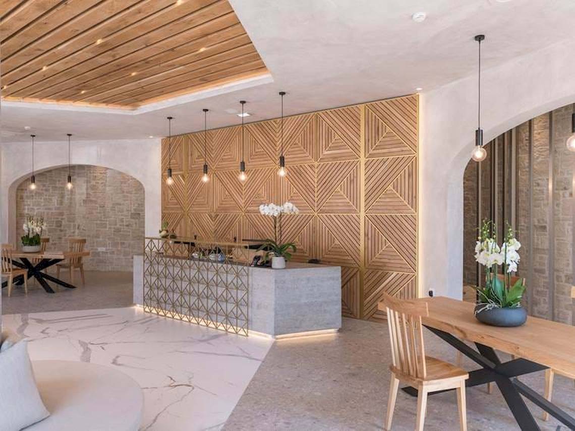 Innenansicht der Lobby im Cactus Mare Hotel mit Marmorboden, Holzdecken und modernen Möbeln.