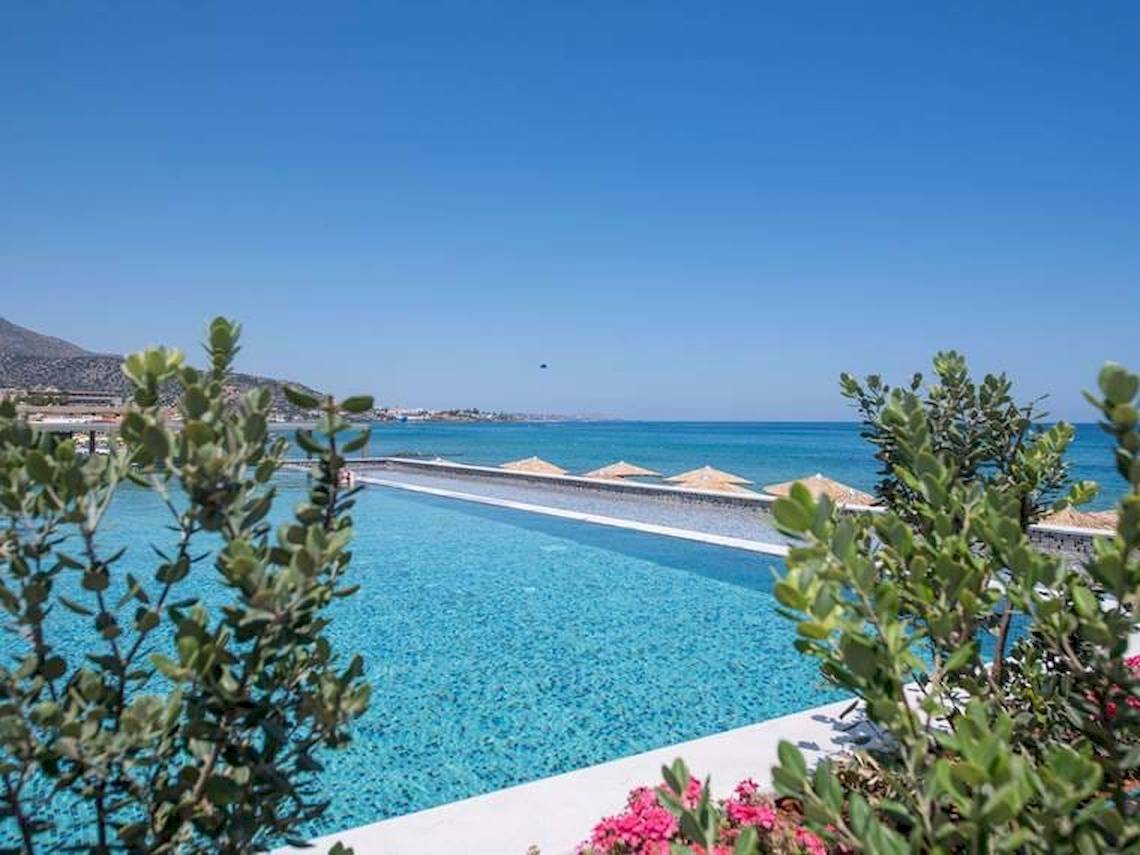 Außenansicht des Pools im Cactus Mare Hotel mit Blick auf das Meer und umliegenden Pflanzen.