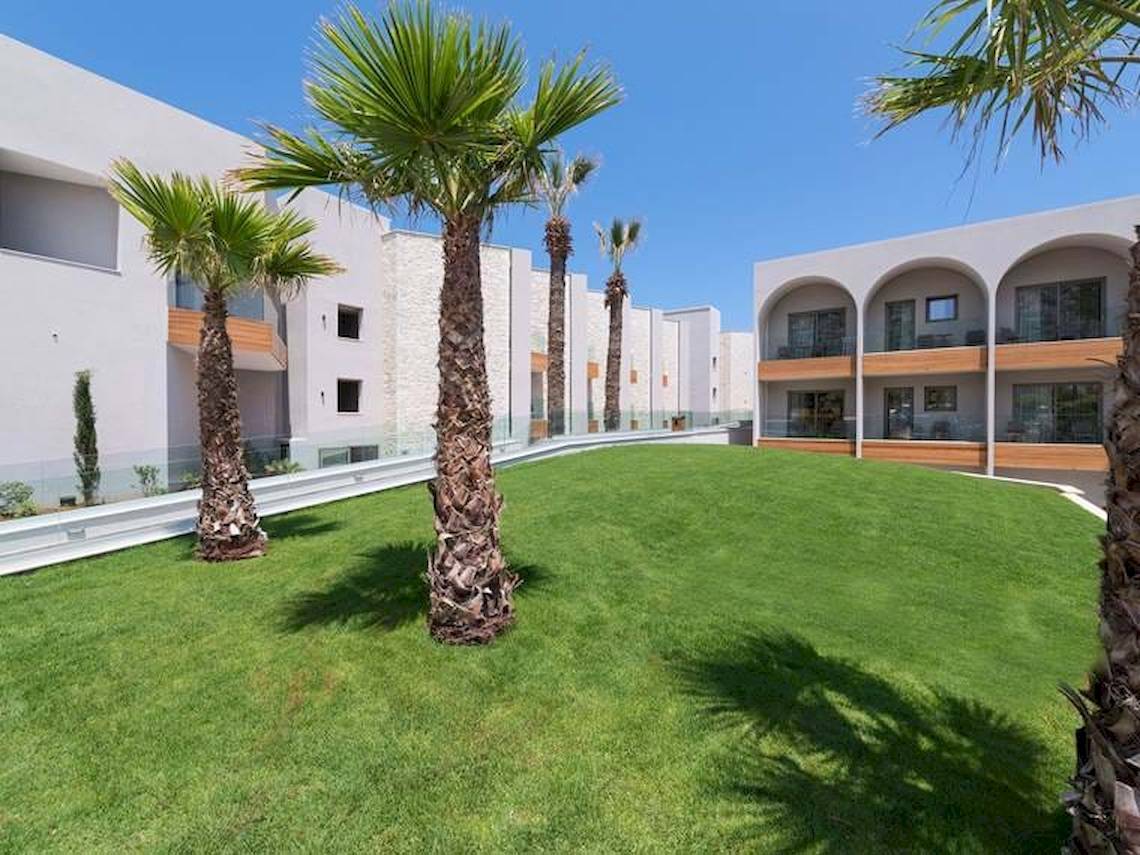 Ein Hotel namens Cactus Mare mit einem gepflegten Vorgarten und Palmen