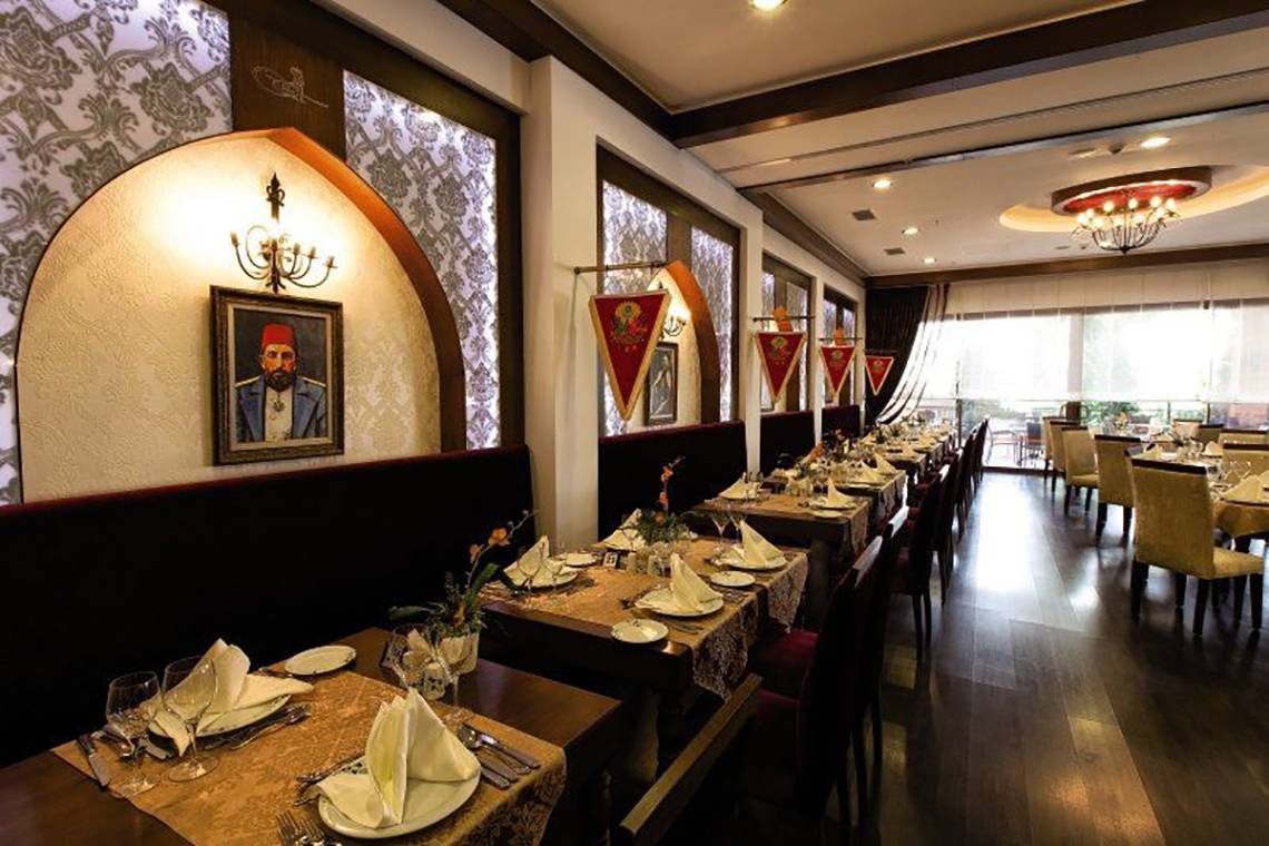 Innenansicht des Restaurants im Adalya ArtSide Hotel mit gedeckten Tischen und dekorierten Wänden.