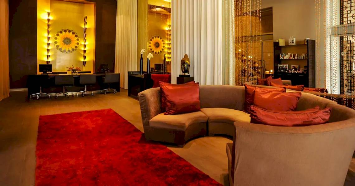 Lobby des Paradisus Playa del Carmen Hotels mit L-förmiger Couch, rotem Teppich und Dekor.