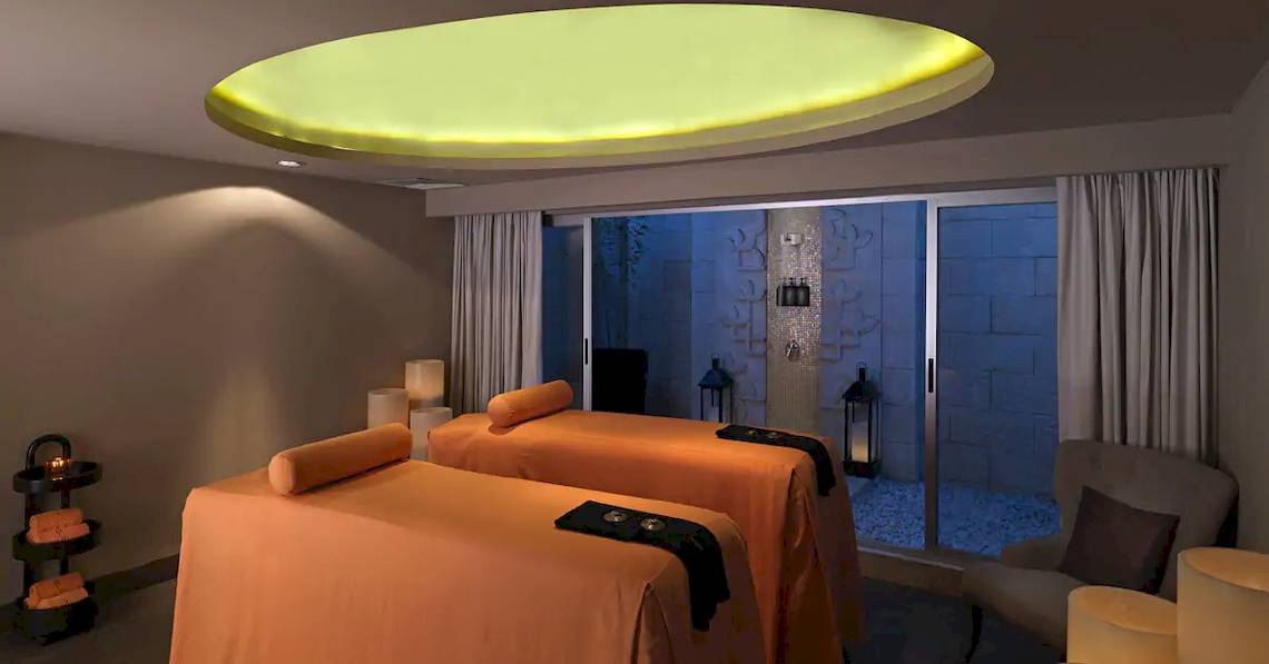 Spa-Behandlungsraum im Paradisus Playa del Carmen mit zwei Massageliegen und einem großen Fenster.