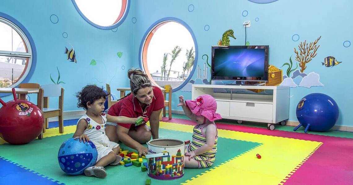 Eine Frau und zwei Kinder spielen in einem farbenfrohen Spielzimmer des Melia Marina Varadero Hotels.