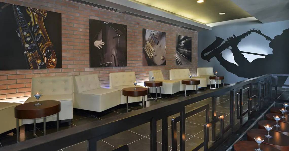 Innenbereich des Melia Marina Varadero Hotels mit weißen Sofas, runden Tischen und Kunstwerken an der Wand.