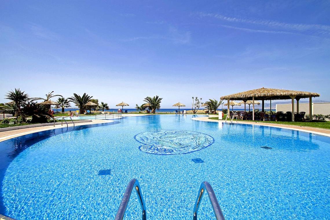 Pool im Plaza Beach Hotel mit Blick auf das Meer und Sonnenschirmen.