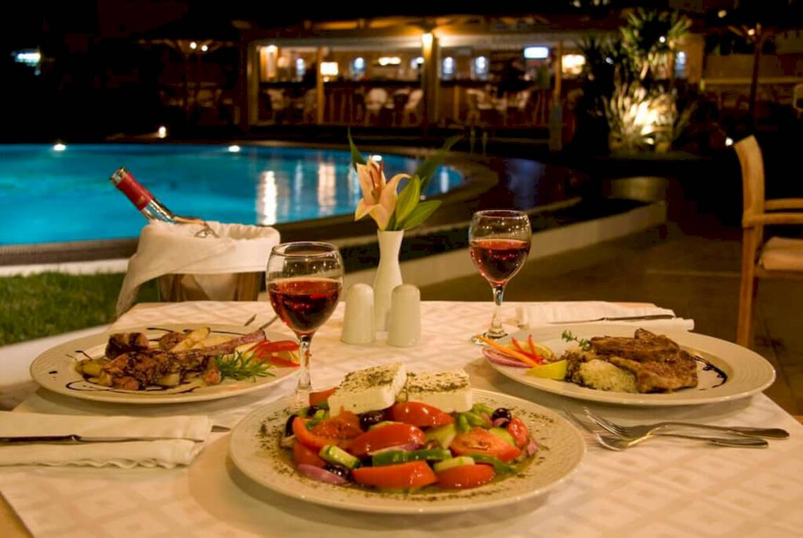 Abendessen beim Pool im Plaza Beach Hotel mit Wein, Salat und Fleischgerichten.