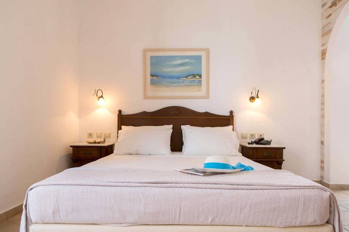 Schlafzimmer im Plaza Beach Hotel mit Bett, Nachttischen und Gemälde an der Wand.