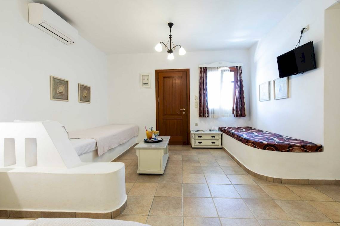 Innenansicht eines Zimmers im Plaza Beach Hotel mit zwei Betten, Tisch und Fernseher.