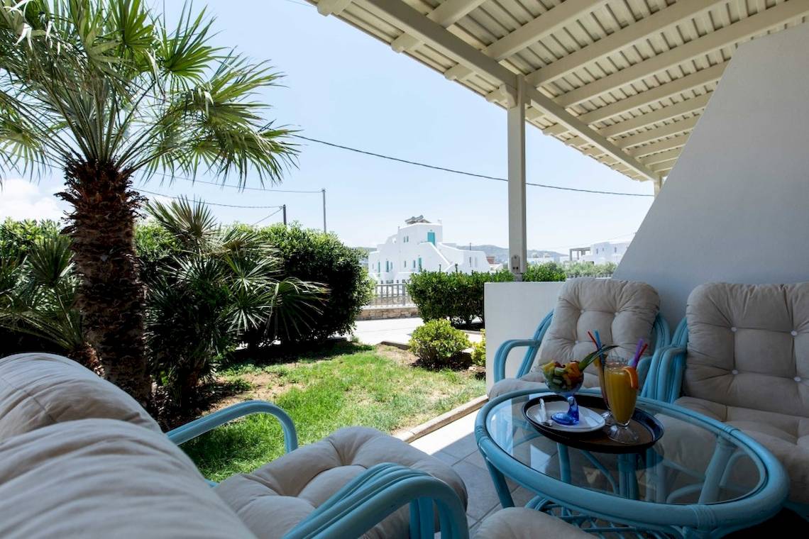 Terrasse des Plaza Beach Hotels mit Blick auf einen Garten und Getränken auf dem Tisch.