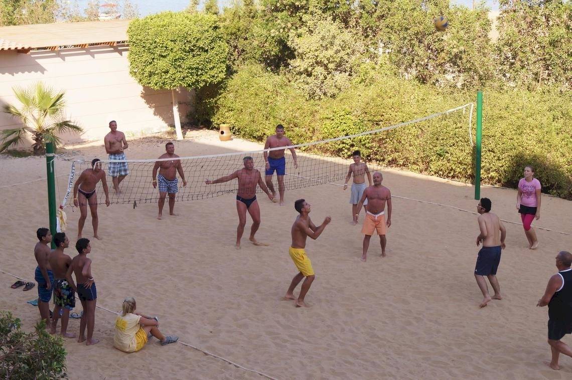 Gruppe von Männern und Frauen spielen Volleyball auf einem sandigen Strand am Sea Star Beau Rivage Hotel.