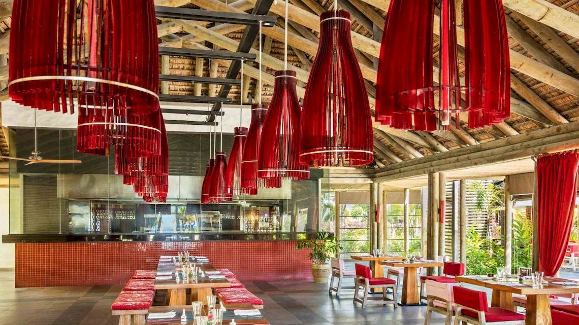 Innenraum des Long Beach Mauritius Restaurants mit roten Vorhängen und Lampen.
